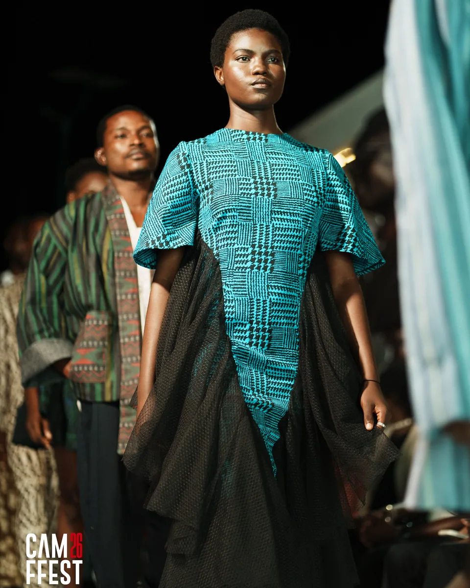 Model in a teal top and sheer black cape