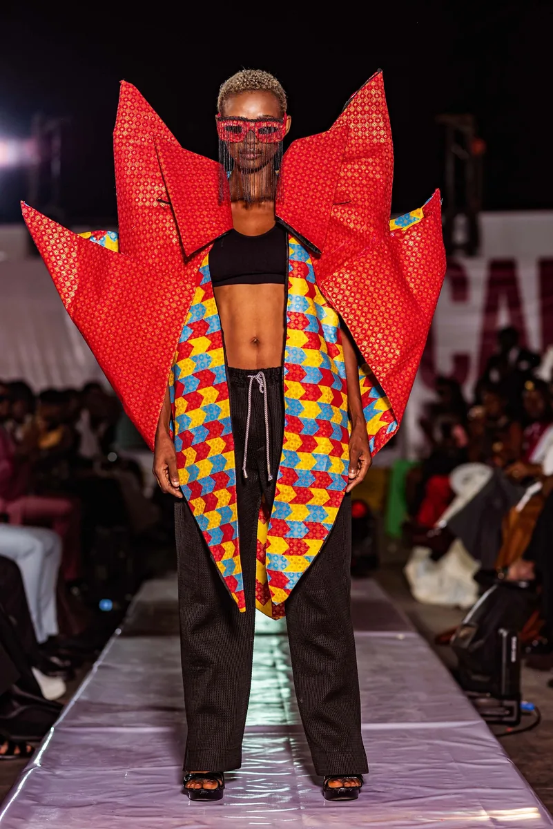 Model in a red winged kente look on the runway